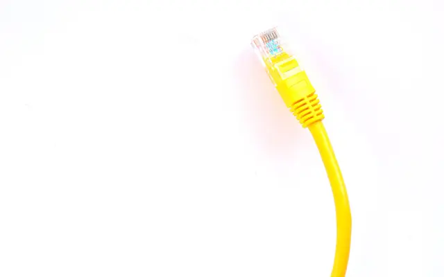 Yellow network cable with a clear plug against a bright white background