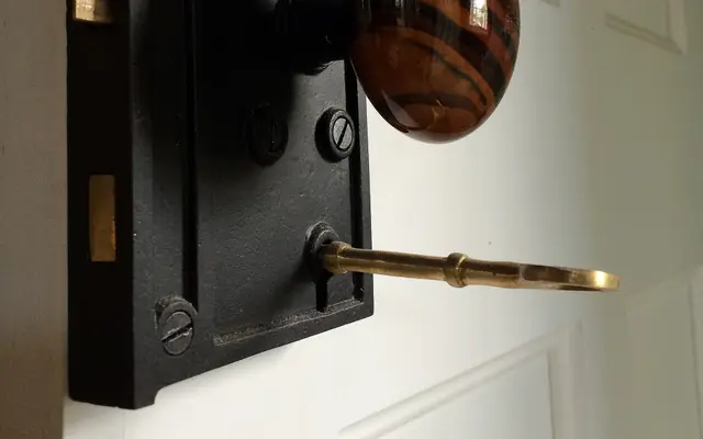 Brass key inserted in a black door lock on a white door