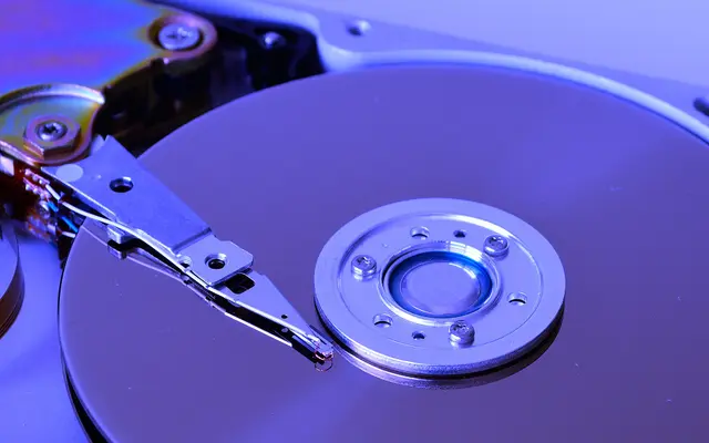 Close-up of a hard drive platter and read arm in blue light