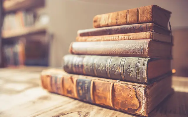Stack of old leather-bound books on a wooden table