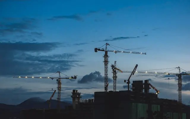 Tower cranes over a building construction site at dusk