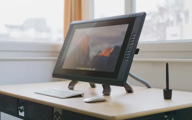 Pen display tablet with stylus and keyboard on a bright studio desk