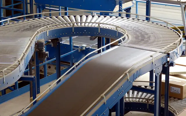 Curving blue roller conveyor system inside a bright distribution warehouse