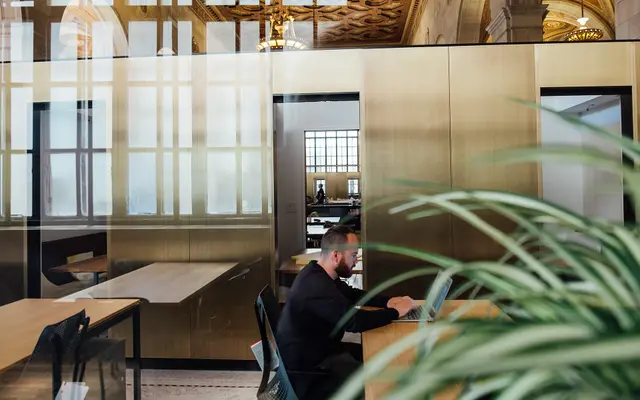 Person working on a laptop at a shared desk in a bright coworking space